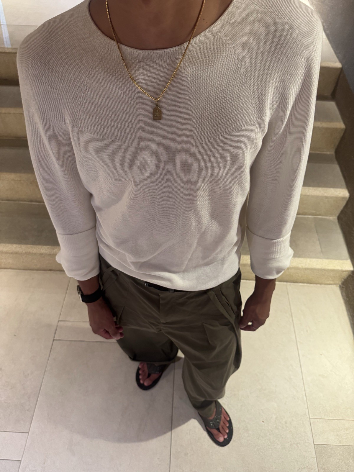 Overhead view of Ratanon in a white knit top and olive trousers