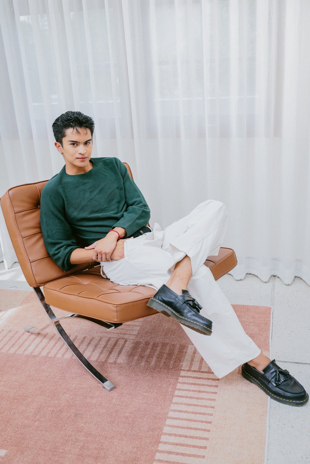 Ratanon in a green sweater, seated in a leather chair