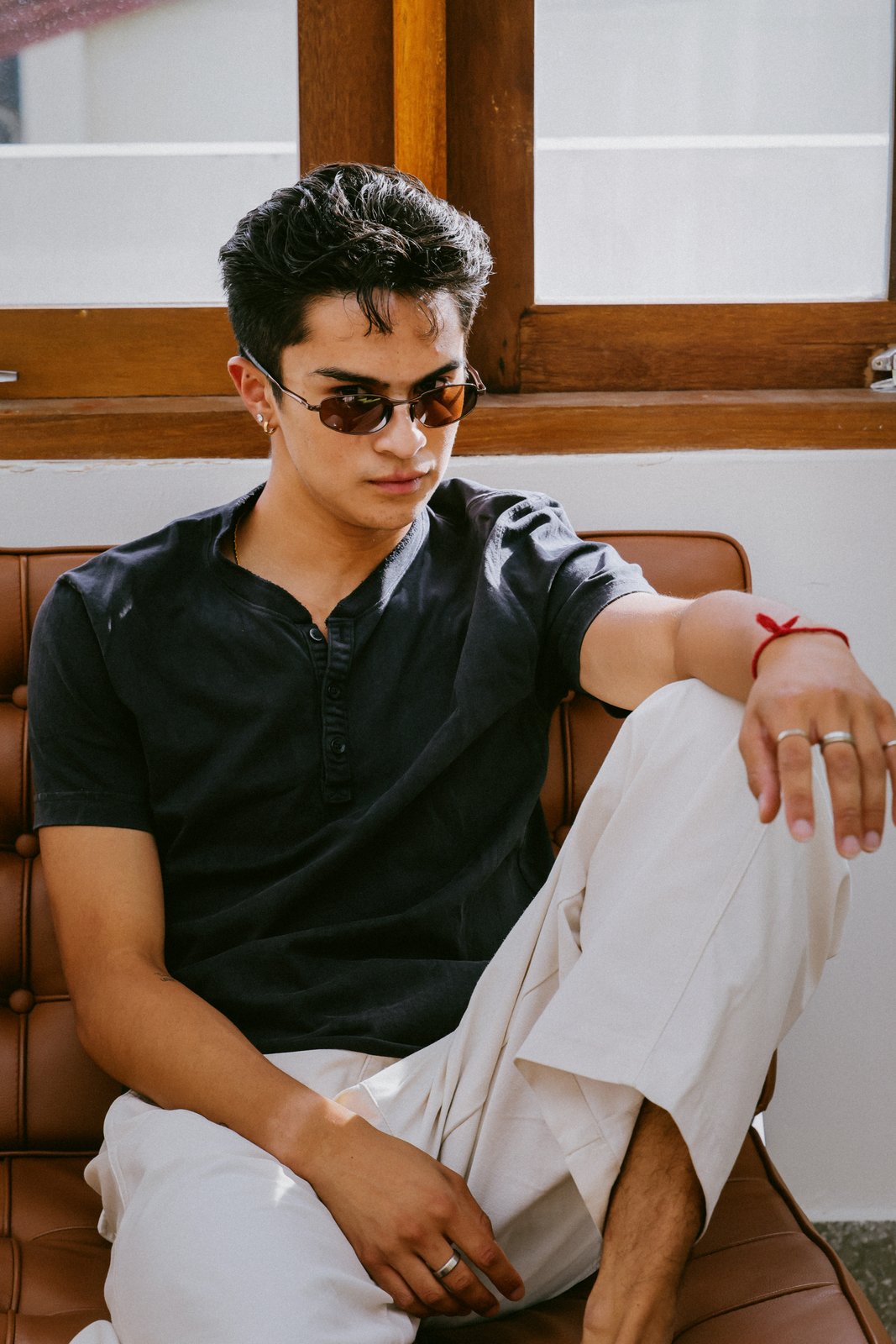 Ratanon in sunglasses, seated on a leather sofa