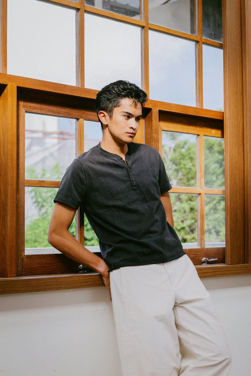 Ratanon in a navy henley, portrait by a wooden window