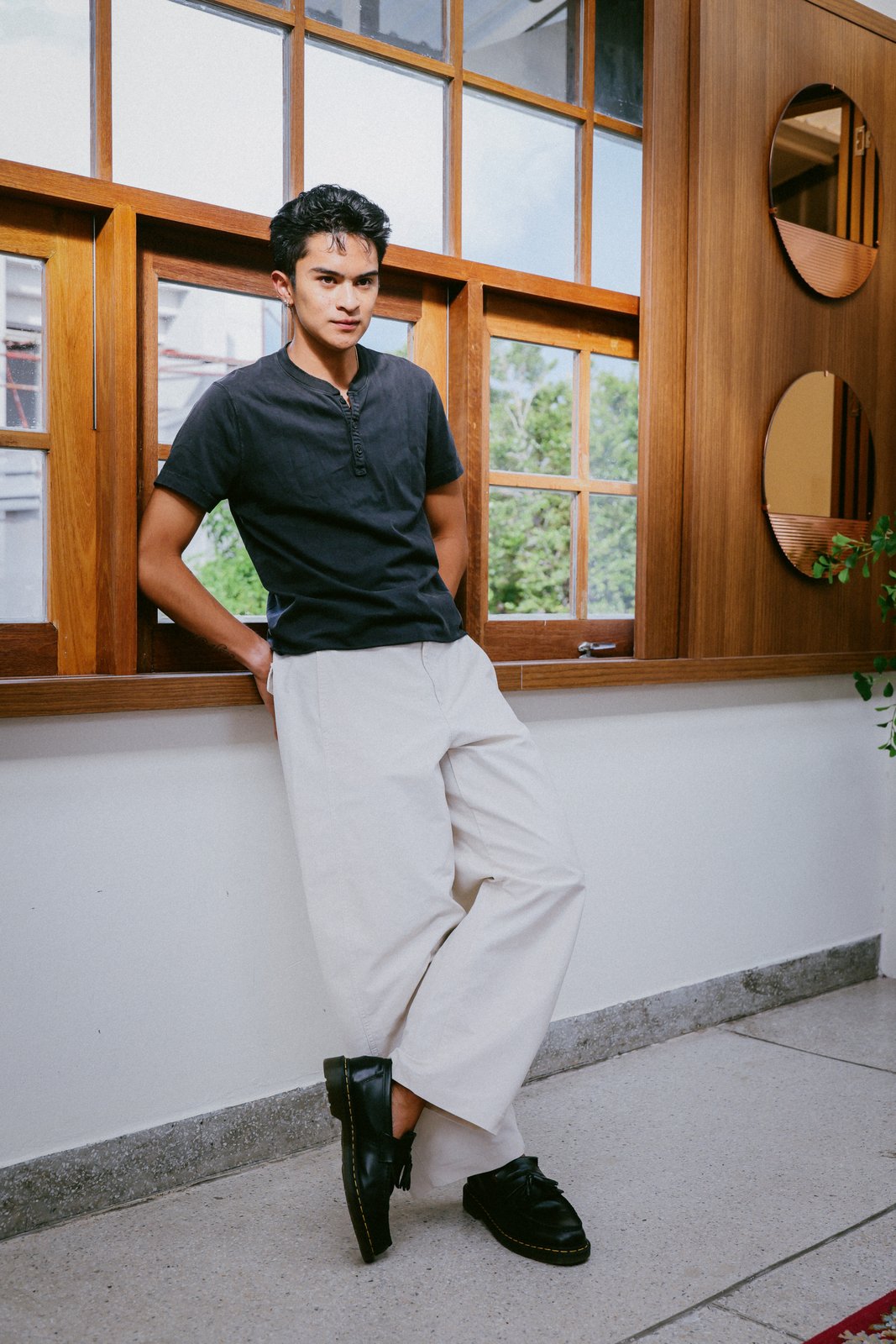 Ratanon in a navy henley, leaning out a window ledge
