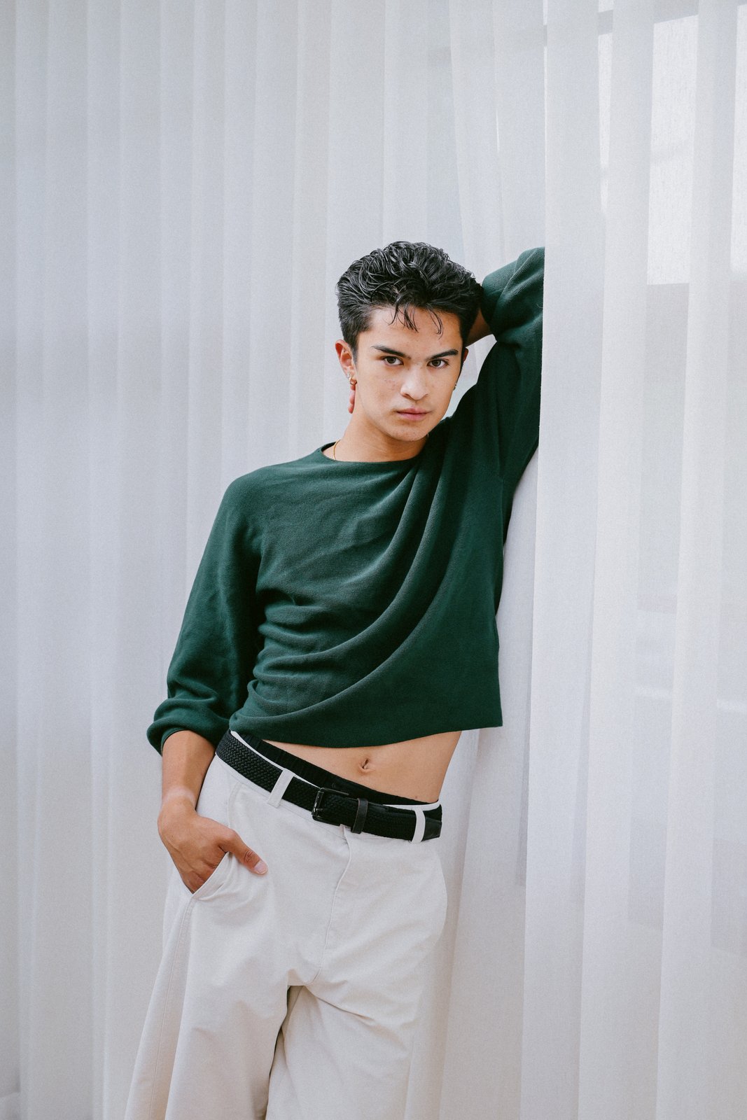 Ratanon in a cropped green sweater against sheer curtains, alternate pose