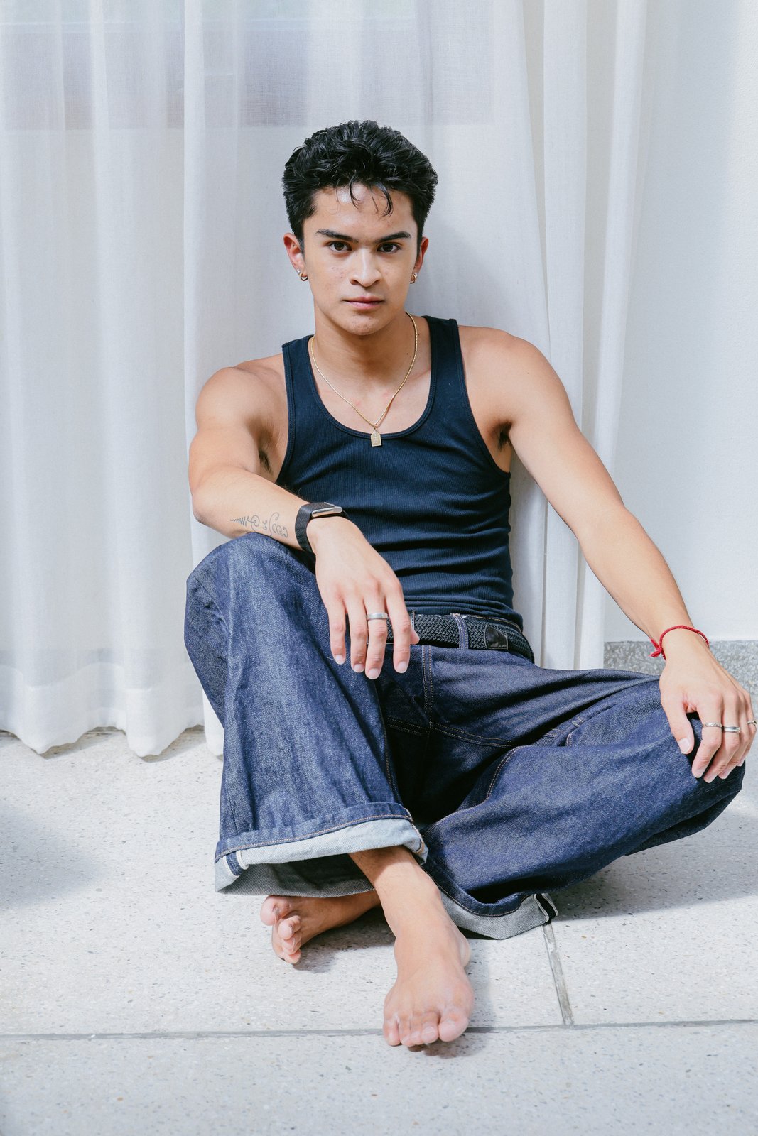 Ratanon in a navy tank top and denim, seated
